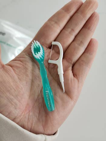 Person holding a greenish and achromatic dental flosser-brush