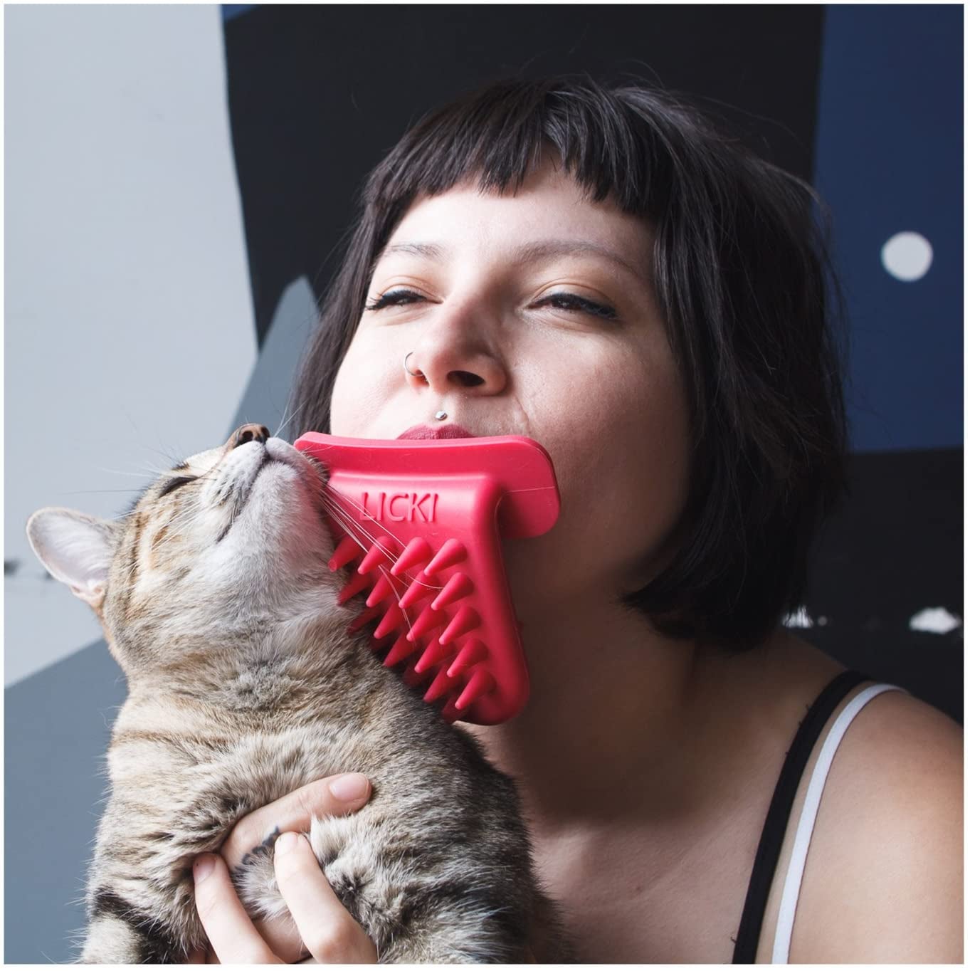 model with the cat brush in their mouth as they brush a cat