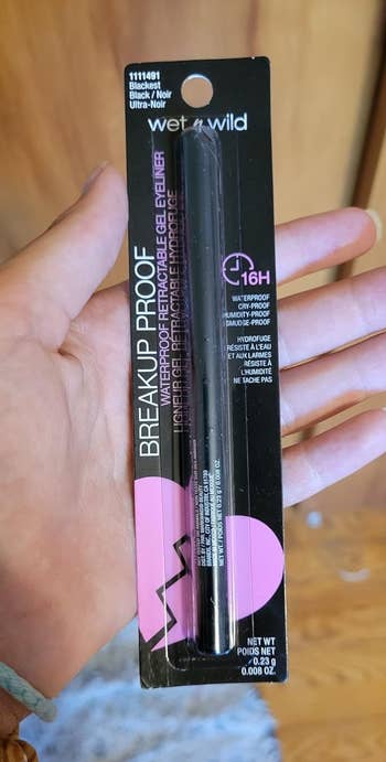 A person holding a Wet n Wild Breakup-Proof black eyeliner package with the product visible