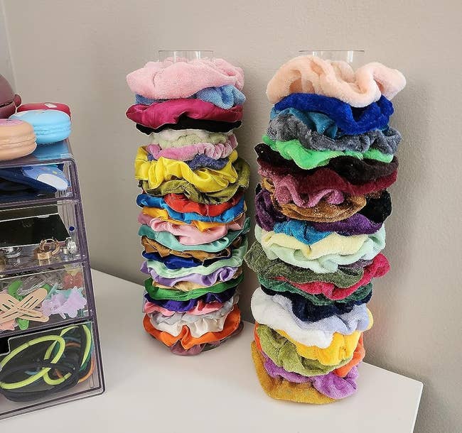 reviewer's two scrunchie holder stands holding stacks of colorful scrunchies