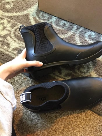 reviewer showing black Ugg rainboots
