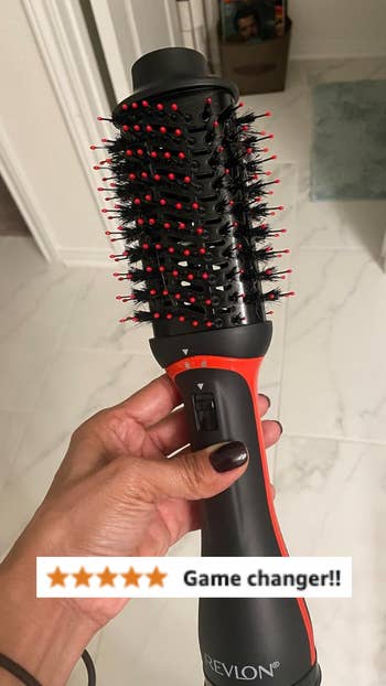 Close-up of a hand holding a Revlon hair dryer brush with a five-star review and the text 