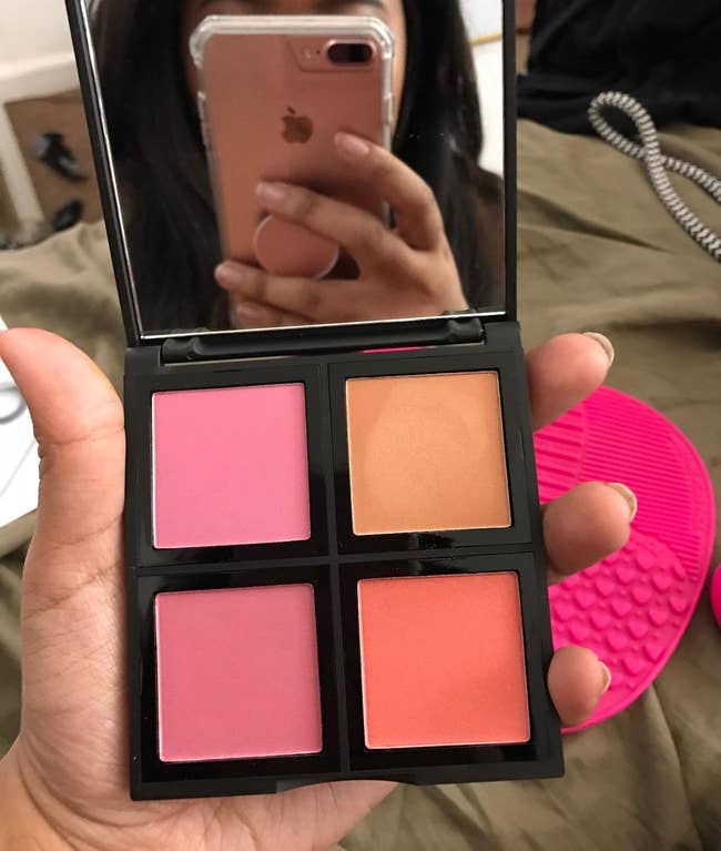 Reviewer holding a four-shade blush palette, reflected in a mirror