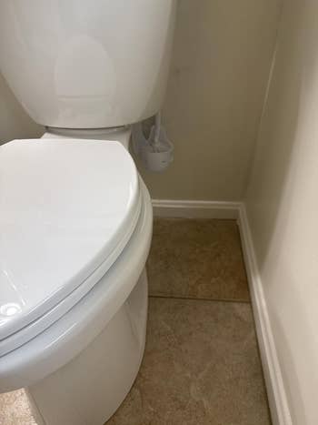 Toilet with attached aerial  freshener hanging connected  the side, placed successful  a tiled bath  corner