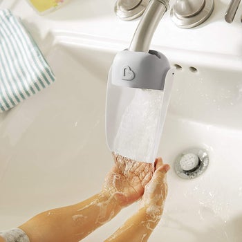 child's hands using faucet extender to wash hands