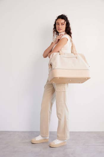 Woman posing with a large beige weekender bag