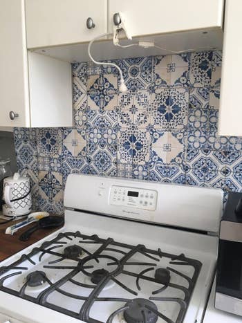 a reviewer's kitchen with a stove in front of decorative tile backsplash, suggesting a home decor theme for shopping