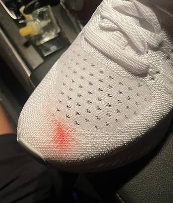 reviewer's white sneaker with red mark
