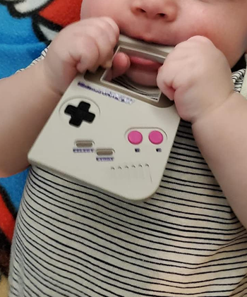 a baby with the teether in their mouth