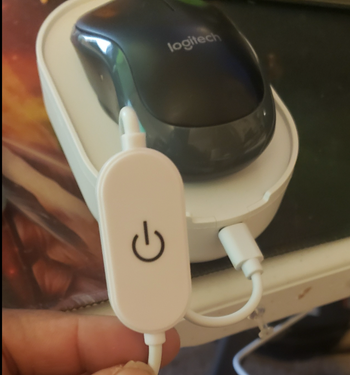 Reviewer holding up the power button on the device 