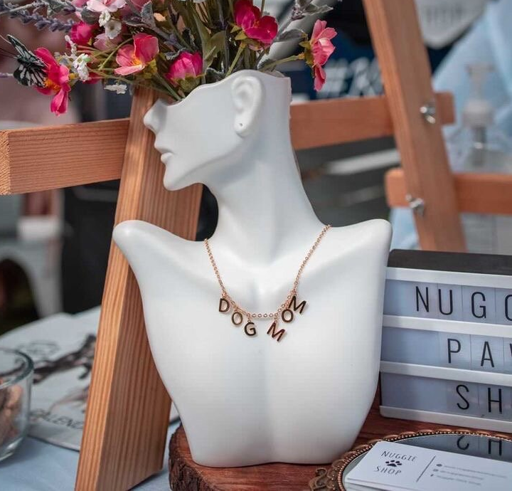 Mannequin wearing gold necklace that reads 
