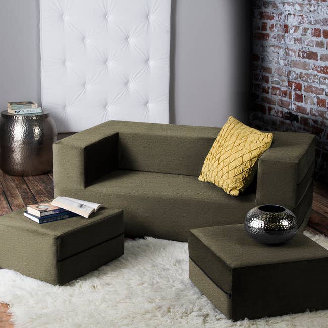 cube sofa with cut out seating and two leveled cushions on the floor beside it 