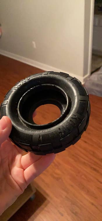Person holding a small, textured rubber tyre  canine  toy