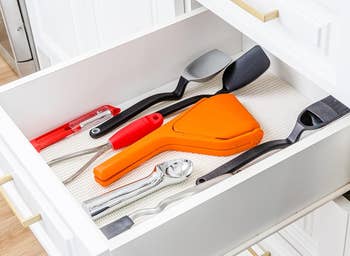 A kitchen drawer with assorted utensils including the fold-flat juicer
