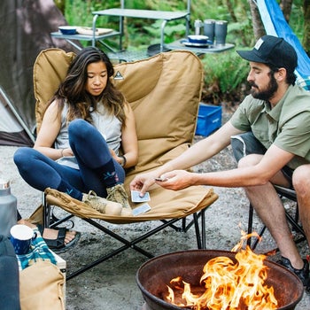 lifestyle photo, people playing cards sitting in mammoth camping chair around a fire pit