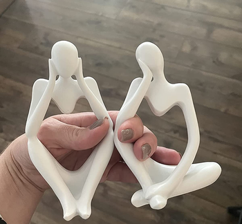 Reviewer holding two white thinker statues with hollow centers