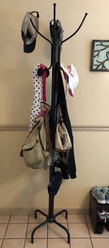 Reviewer image of the black coat rack with coats, bags, hats, etc.