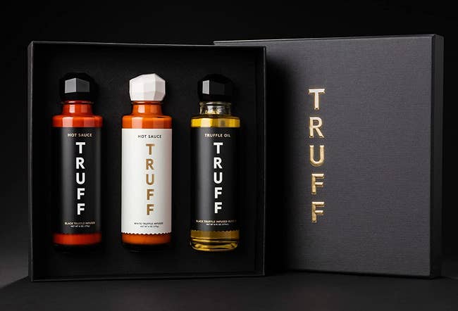 a black gift box filled with two different TRUFF hot sauces and a bottle of truffle oil 