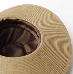 Wide-brimmed beige sun hat with brown interior lining displayed against a white background