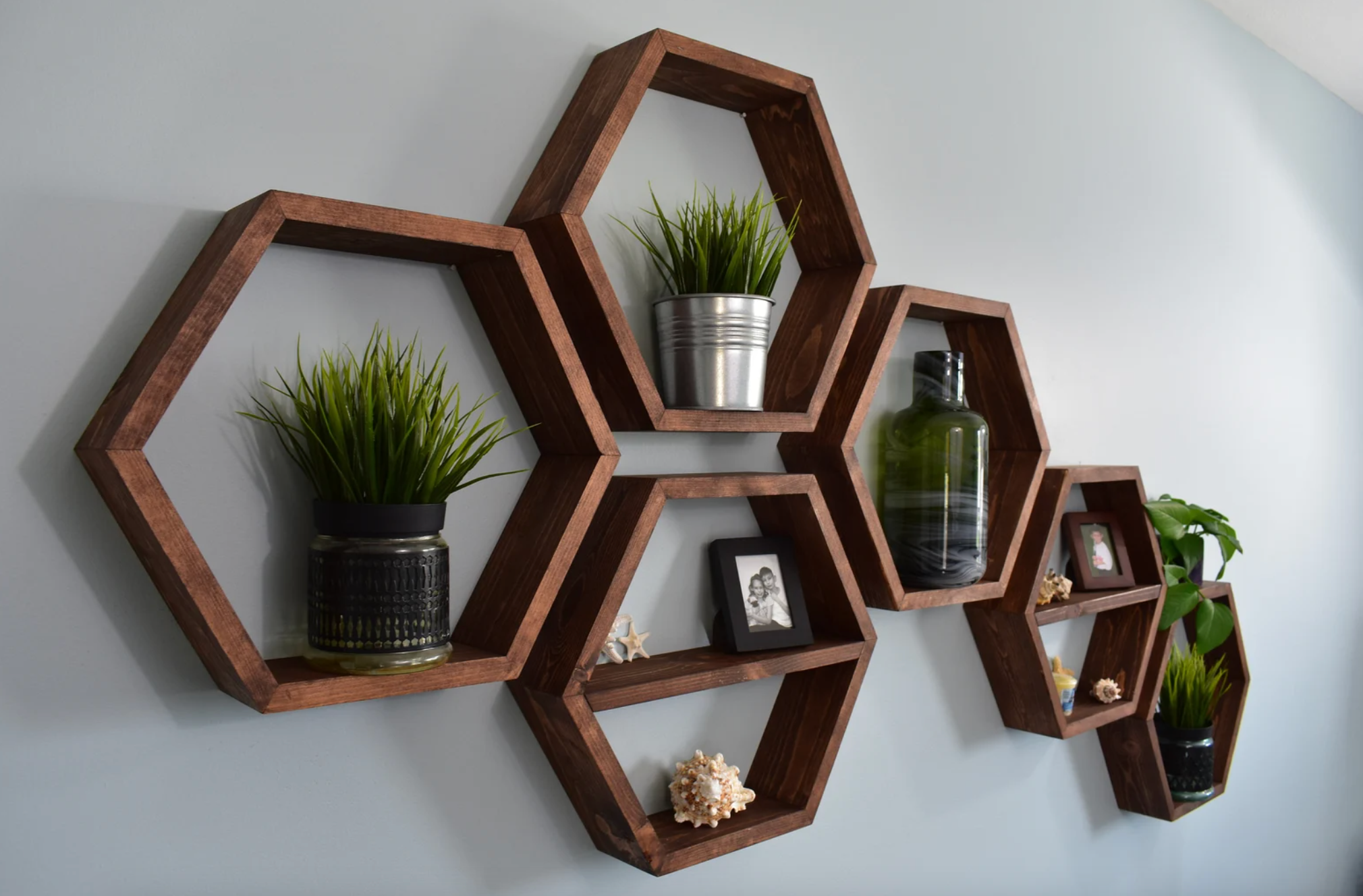 hexagon shelves on wall holding various items like plants, picture frames, and small pieces of decor