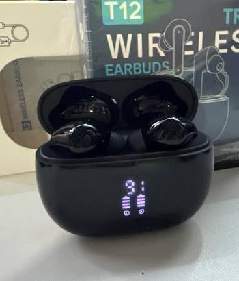 Wireless earbuds successful  a charging case, displayed with packaging labeled 