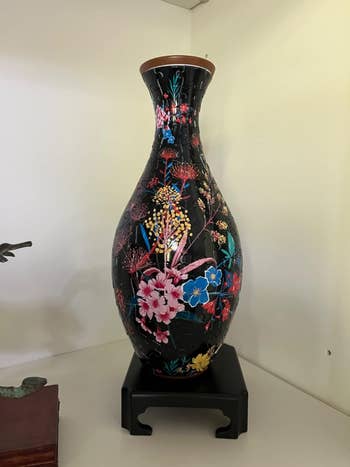 A reviewer's completed black vase with colorful floral design