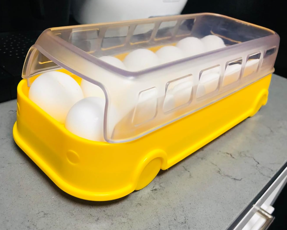 A yellow school bus shaped egg tray with a transparent top shaped like windows on.a bus 
