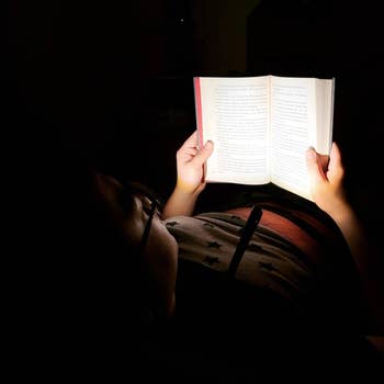 reviewer photo of them using the light around their neck, showing how it only lights up the book in their hands