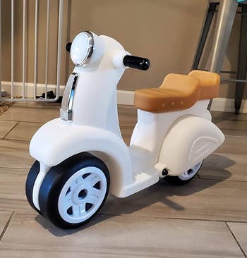 Child's toy scooter in a house hallway, resembling a classic moped design, suggesting a stylish choice for kids' play