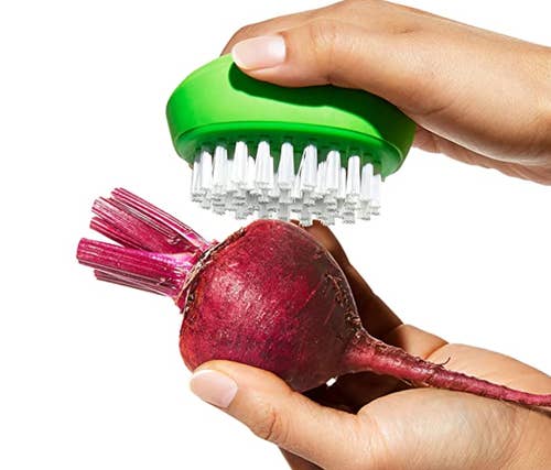 A model's hand using the brush on a radish
