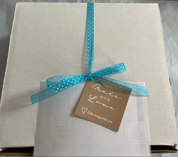 White cardboard box  with blue polka dot ribbon with brown notecard attached