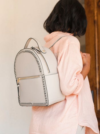 woman carrying beige mini backpack