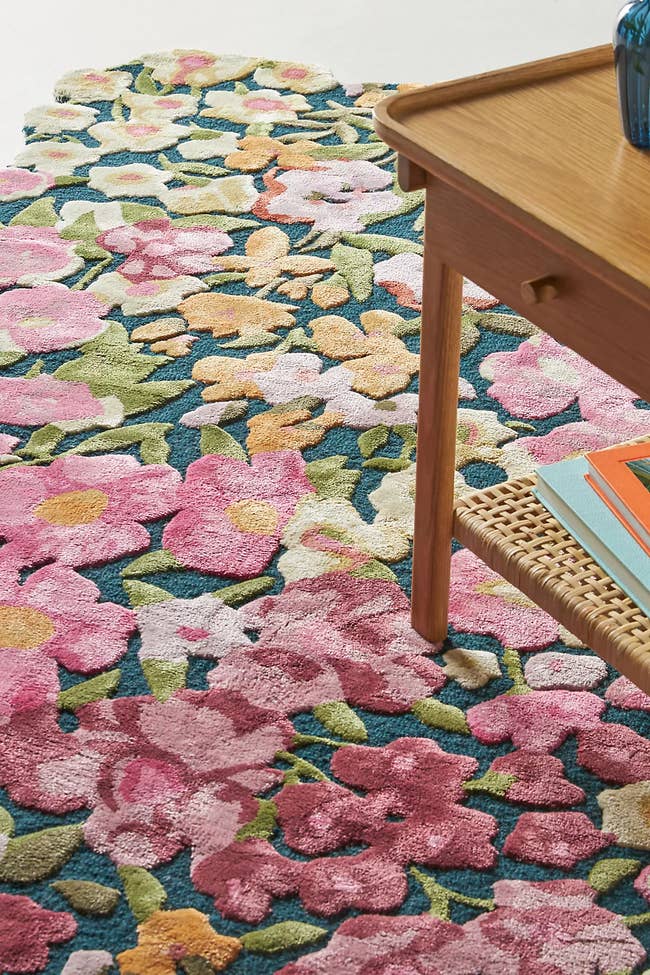 Floral rug with a mix of large pink, green, and yellow flowers beneath a wooden table in a home setting