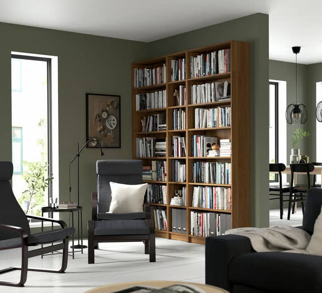 Living country   with a ample  woody  bookshelf filled with books, modern   chairs, a level  lamp, and eating  country  successful  the background