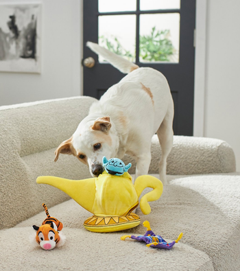 dog pulling small plush toys out of large plush lamp