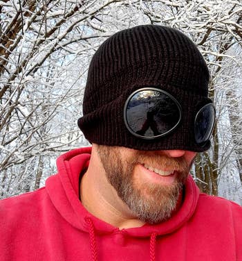 Reviewer wearing product in black with goggles on and a red sweatshirt
