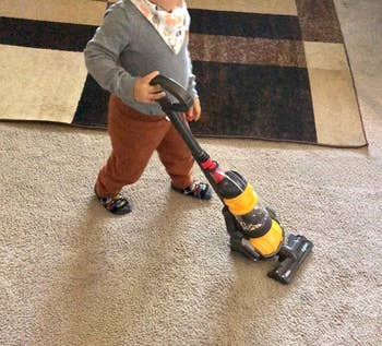 image of reviewer's child using the mini dyson vacuum on carpet