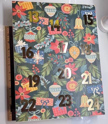 Festive advent calendar container with numbers 13-24, featuring holiday-themed illustrations of ornaments, presents, and greenery