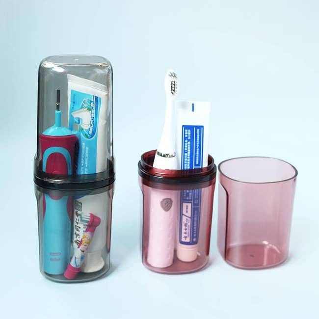 gray container closed and holding toothbrush with toothpaste, which is next to the open red container holding similar items and showing the lid as a cup 