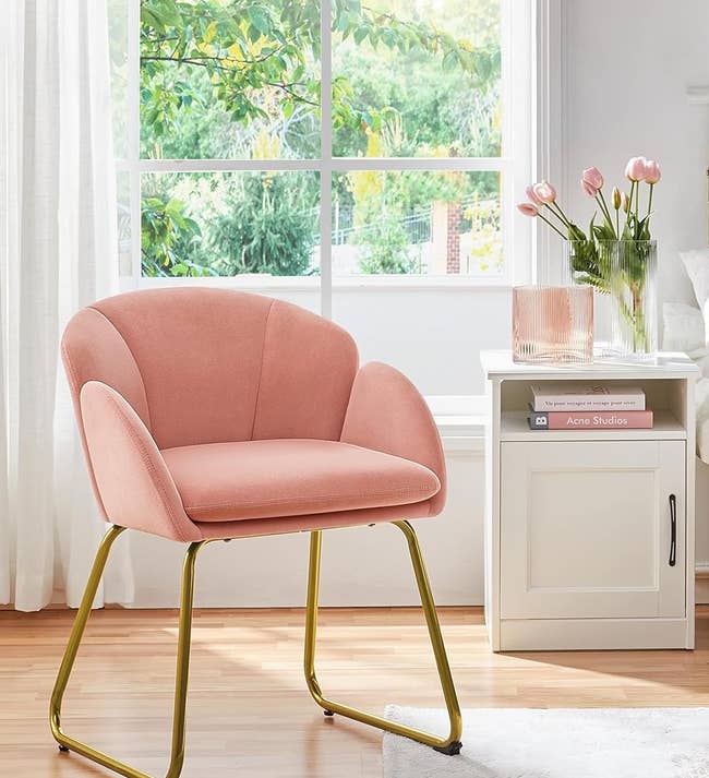 Pink chair with gold legs in a bright, modern bedroom set-up