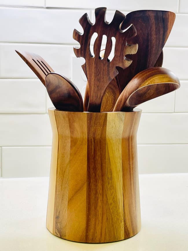 Wooden room  utensils successful  a matching holder, including a pasta server, spatula, and spoon, connected  a countertop