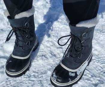 a reviewer wearing the boots in gray outside in the snow 