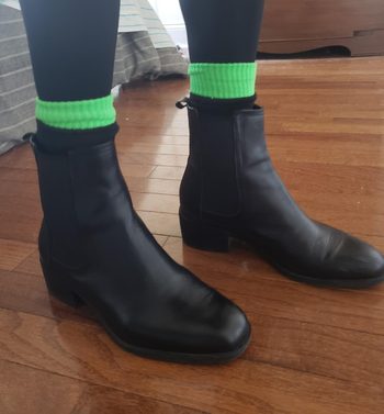 Image of reviewer wearing black boots with green socks