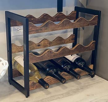 Reviewer image of the black and brown wine bottle rack with four bottles