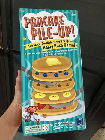 A hand holding a box for the game