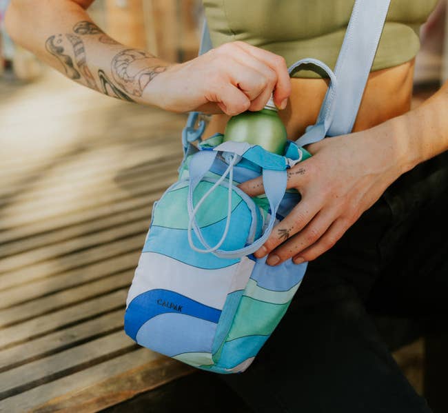 model placing water bottle in blue-patterned bag