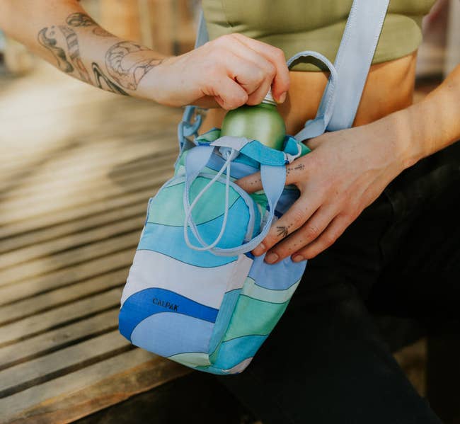 model placing water bottle in blue-patterned bag