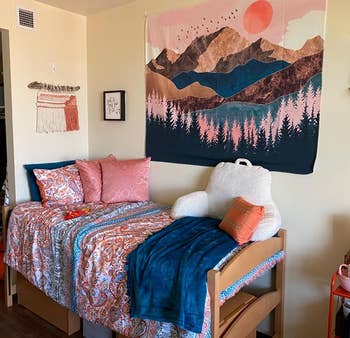 reviewer with the mountain sunset tapestry hanging above their bed in a dorm 