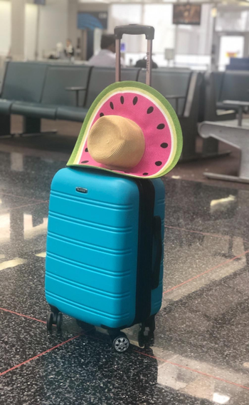 reviewer photo of bright turquoise suitcase in the airport