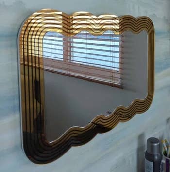 reviewer photo of the gold mirror hung horizontally on a wall